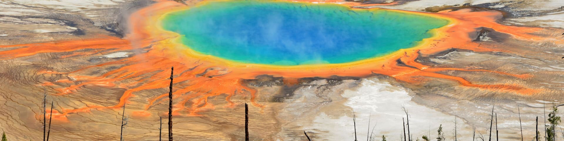 A vibrant geothermal pool with a surrounding barren landscape.