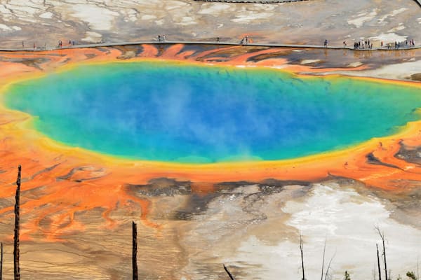 A vibrant geothermal pool with a surrounding barren landscape.