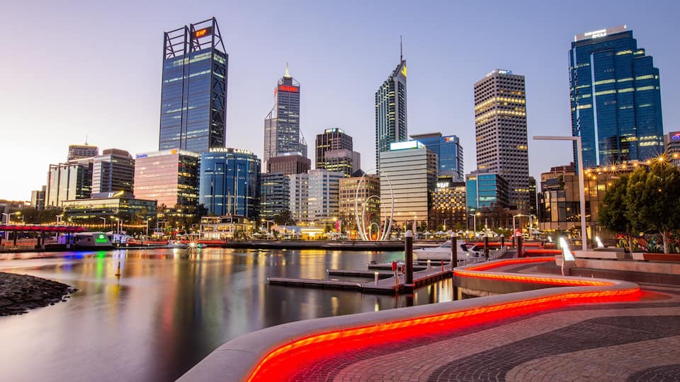 A city skyline with modern skyscrapers, a waterfront, and a well-lit pedestrian area.