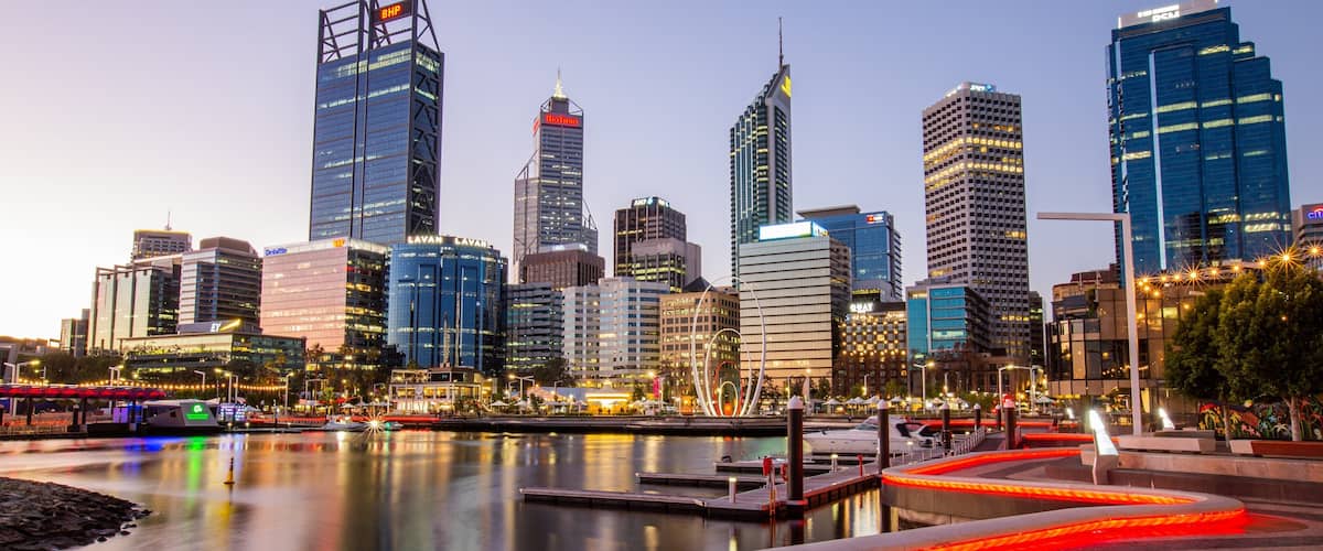 A city skyline with modern skyscrapers, a waterfront, and a well-lit pedestrian area.