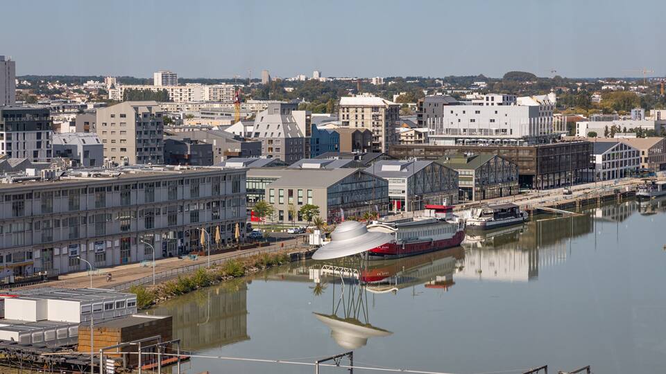 A river with a boat, buildings, and a bridge.