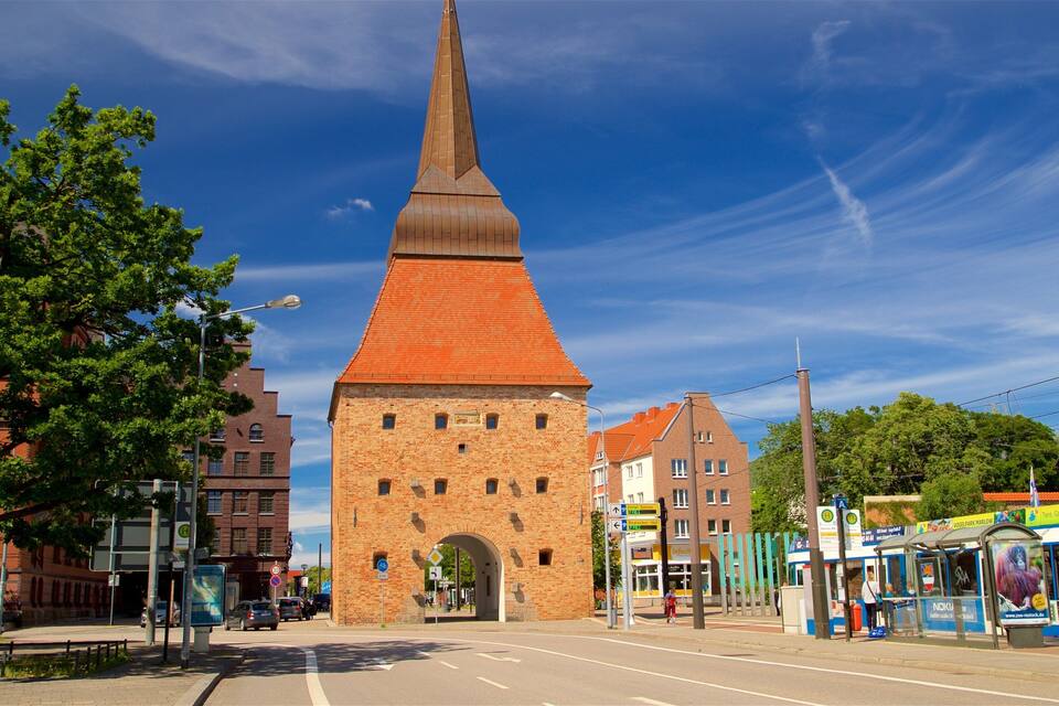 Una iglesia histórica con una aguja alta, rodeada de edificios modernos y una parada de tranvía.