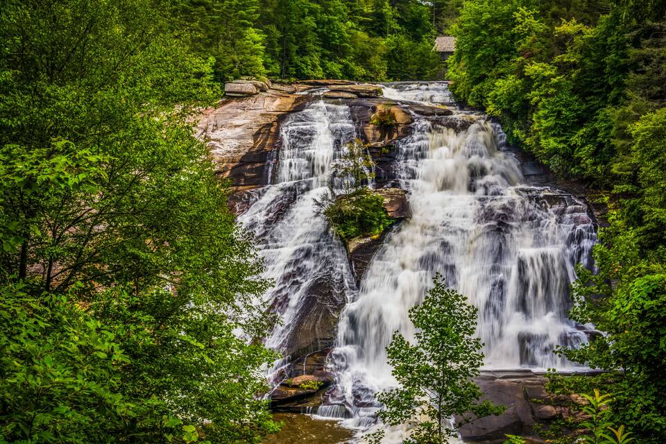 A multi-tiered waterfall surrounded by dense green foliage.