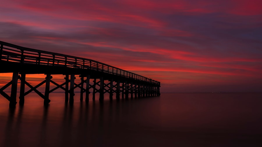 Dramatic red sunset viewed from Bayshore Waterfront Park, New Jersey featuring fishing pier on the background
