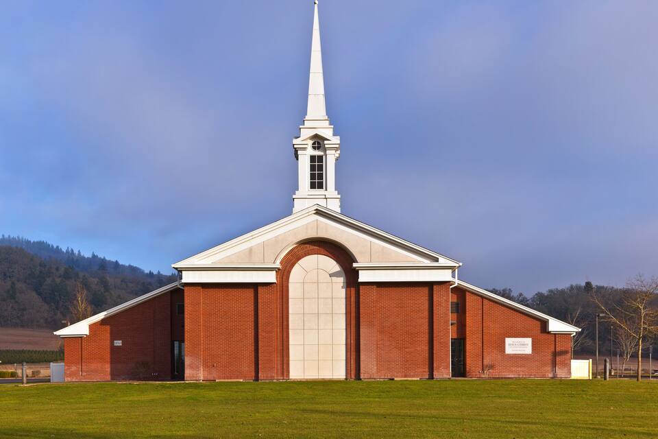 A brick church with a white steeple and a large arched entrance.