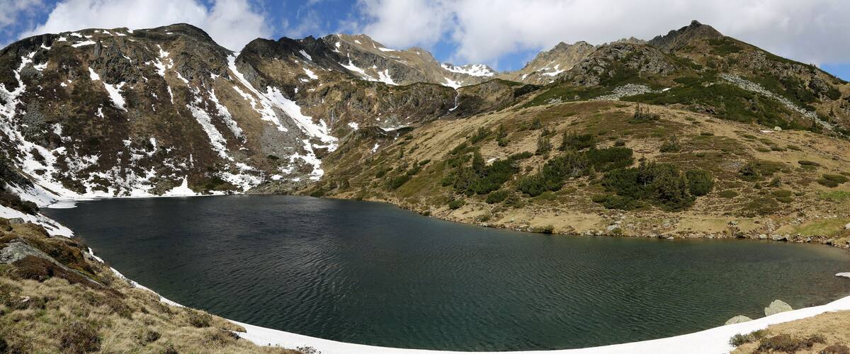 A mountain lake surrounded by rocky terrain and patches of snow.