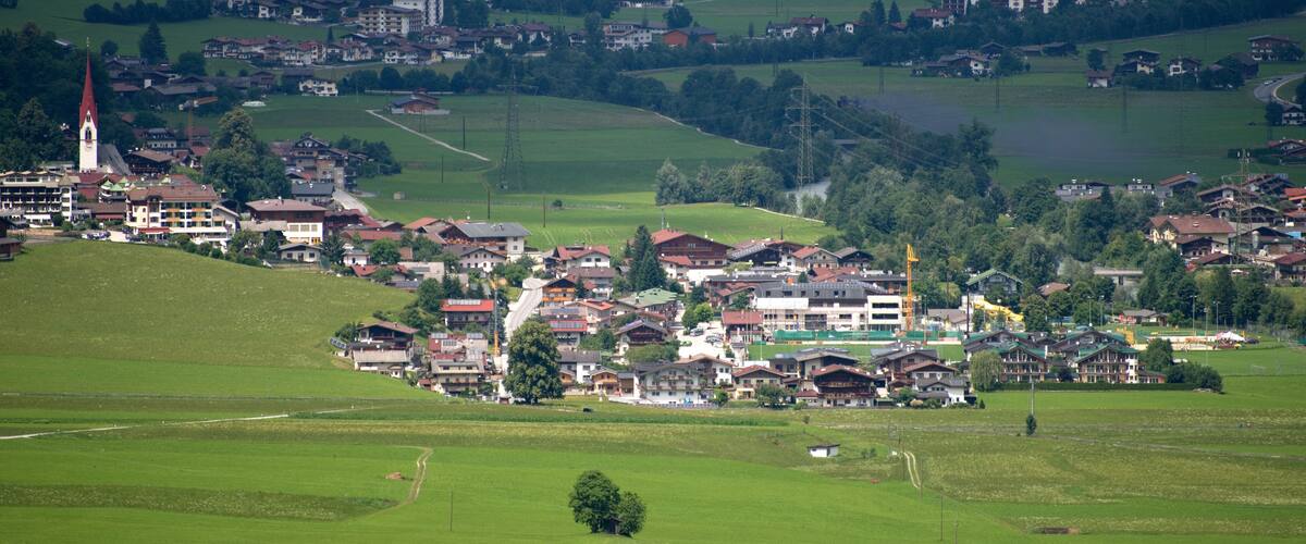 A town nestled in a valley with a prominent church steeple, surrounded by lush green fields and scattered houses.