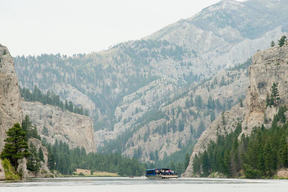Un bateau sur une rivière, entouré de falaises rocheuses et de forêts denses.