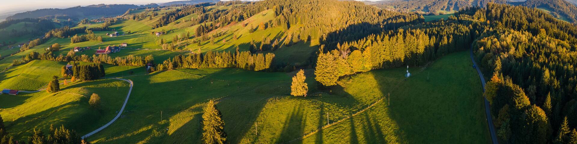 A rural landscape with rolling hills, a winding road, and scattered houses.