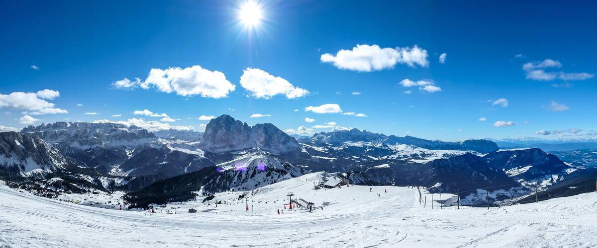 A snow-covered mountain landscape with ski slopes, a prominent peak, and a clear blue sky.