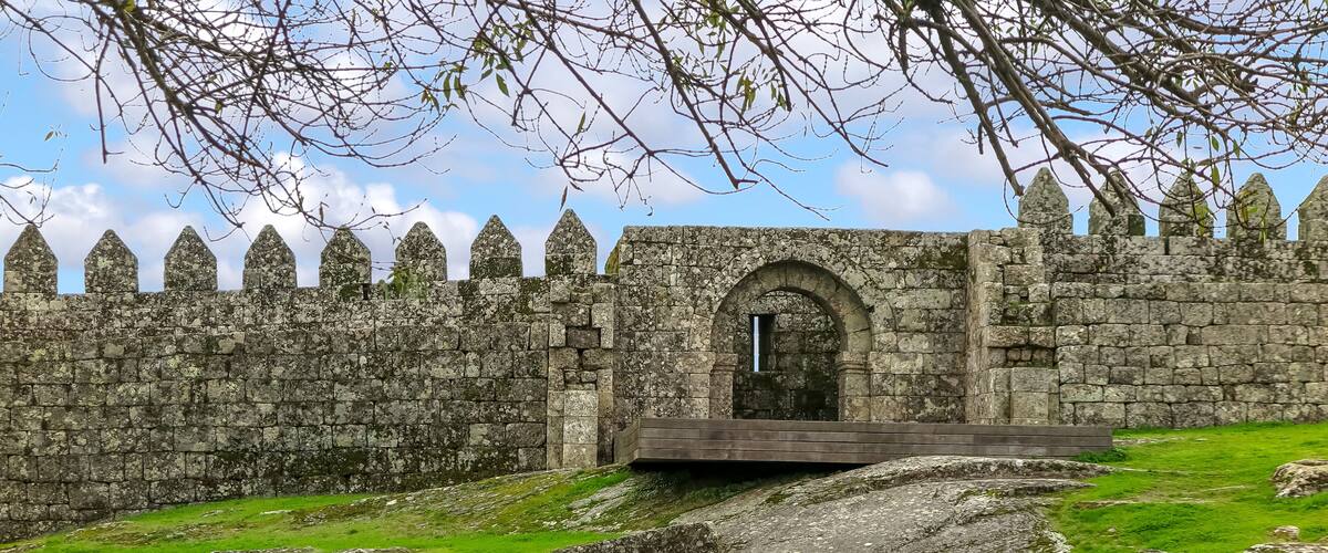 A stone wall with pointed tops and a central arched entrance.