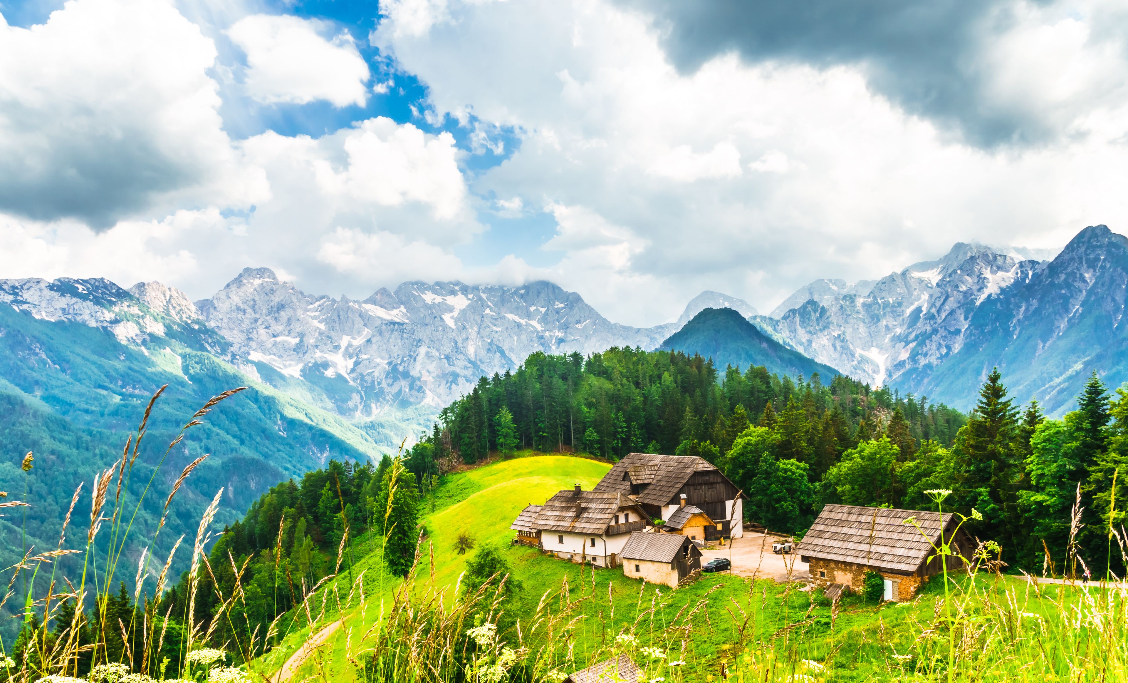 Un village de montagne aux maisons traditionnelles, entouré d’une végétation luxuriante et dominé par d’imposants sommets.
