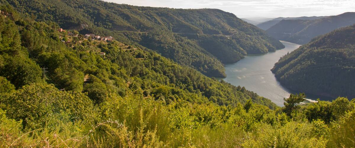 A river valley with lush green hills and scattered houses.