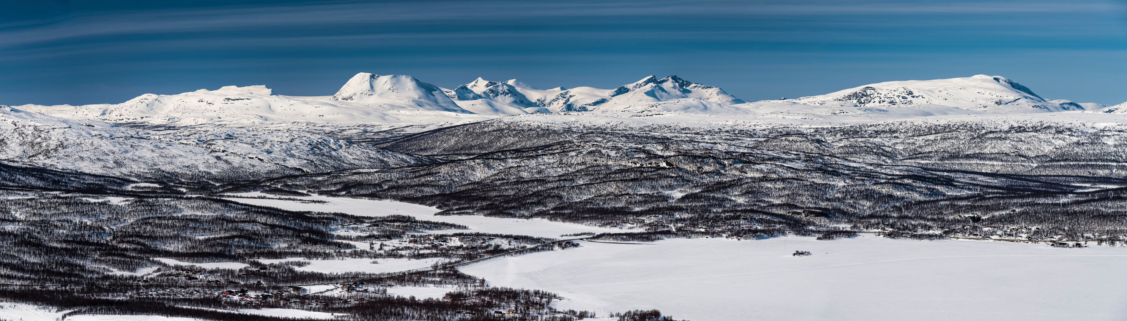 Panorama view at the Joesjo lake with mountain range behind it, very close to Atoklinten, Lappland, Northern Sweden. Bright sunny day, snow, blue skies, much copy space