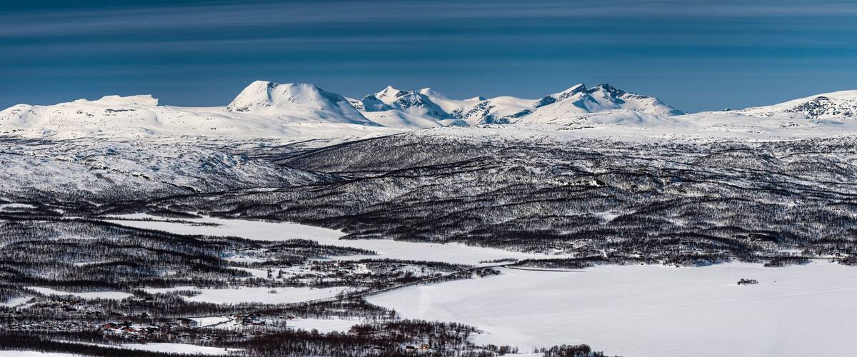 A snow-covered mountain range with a town in the foreground.