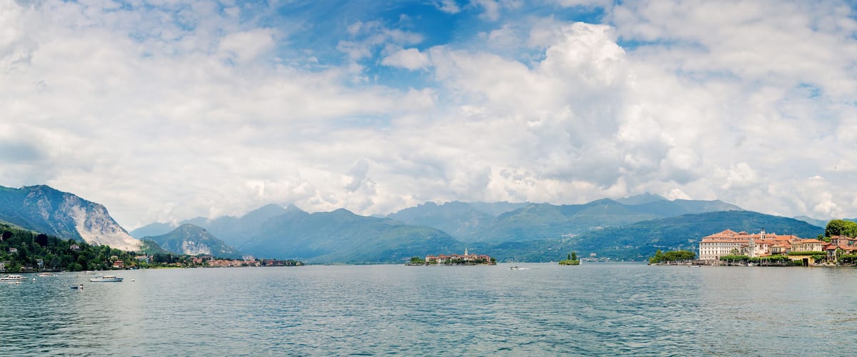A lake with boats, mountains, and buildings along the shore.