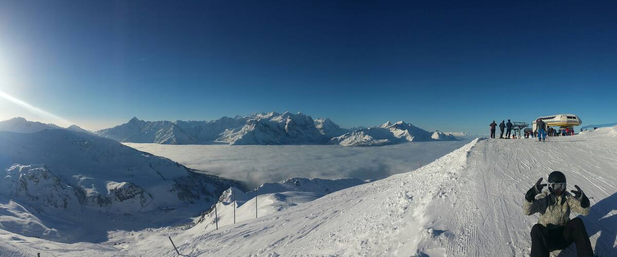 A snow-covered mountain landscape with a clear sky and a sun shining from the left.