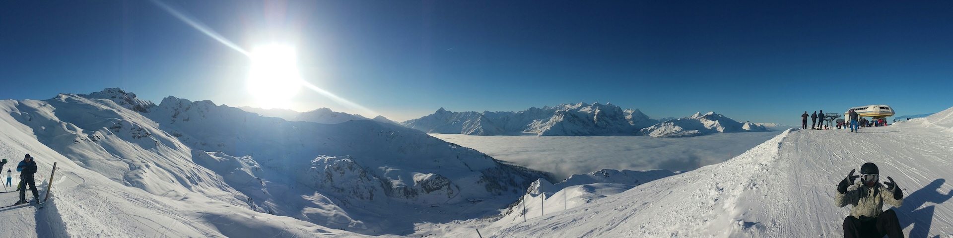 A snow-covered mountain landscape with a clear sky and a sun shining from the left.