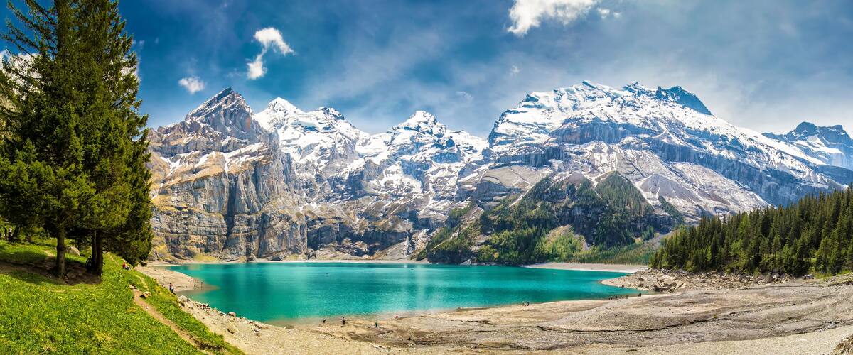A turquoise lake surrounded by snow-capped mountains and dense forests.