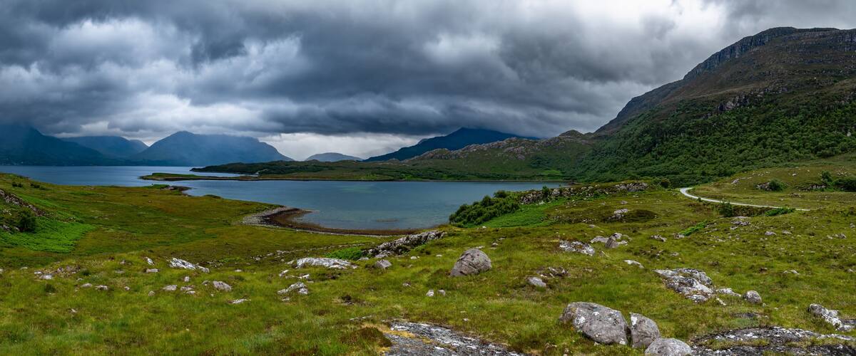 A lake surrounded by mountains and grassy fields.
