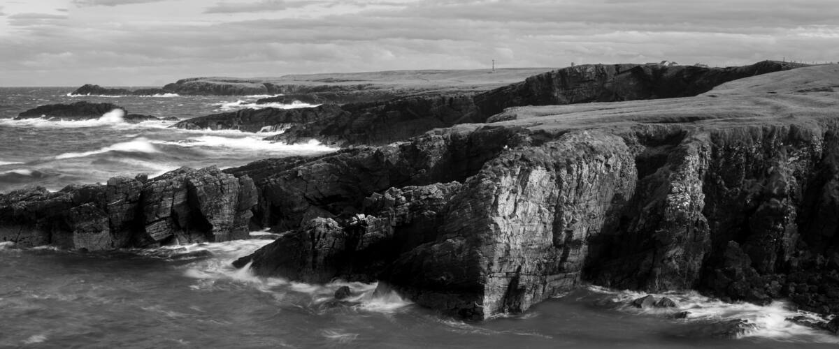 A rugged coastline with rocky cliffs and turbulent sea waves.