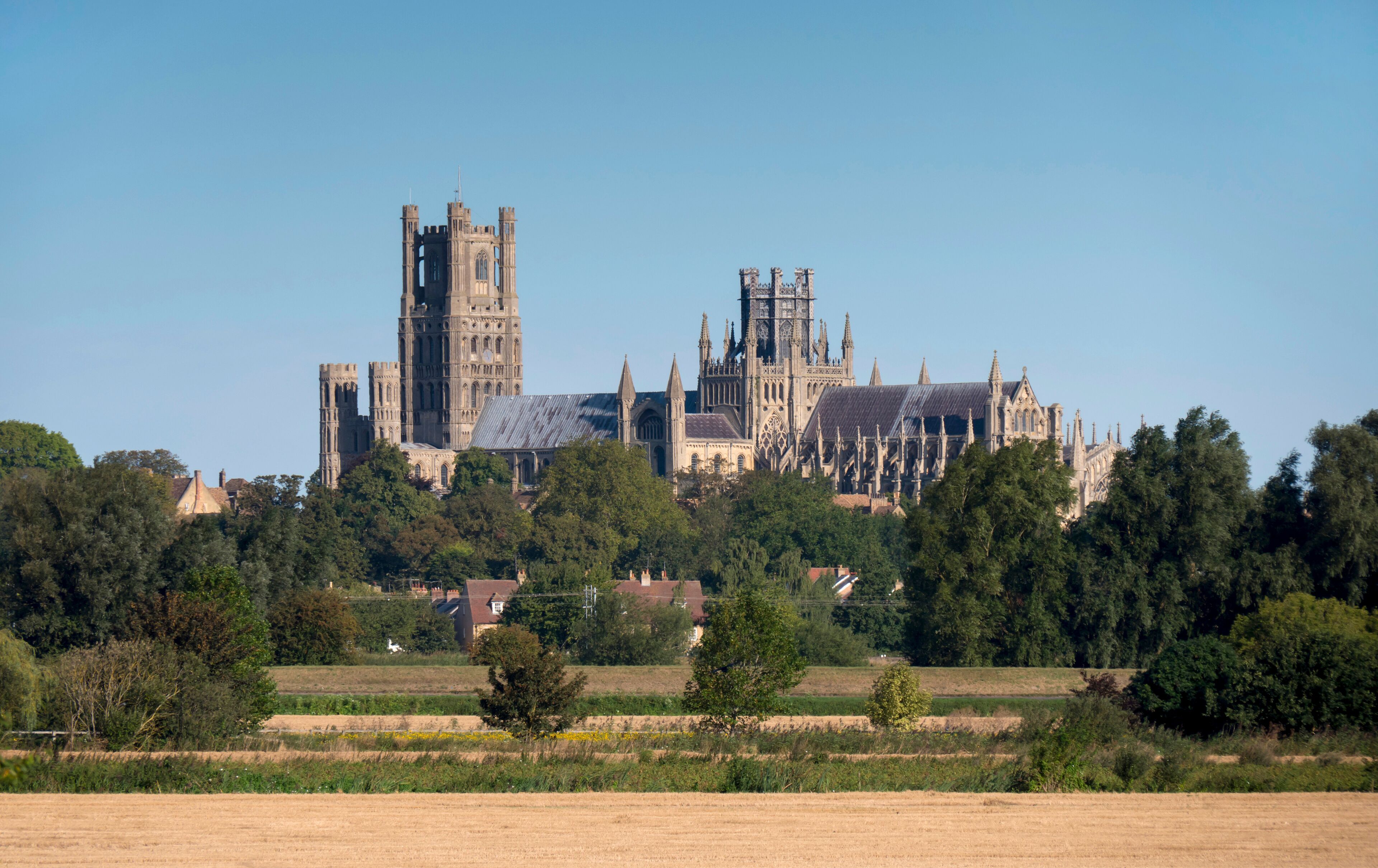 A large Gothic cathedral with twin towers and intricate architecture, surrounded by fields and trees.