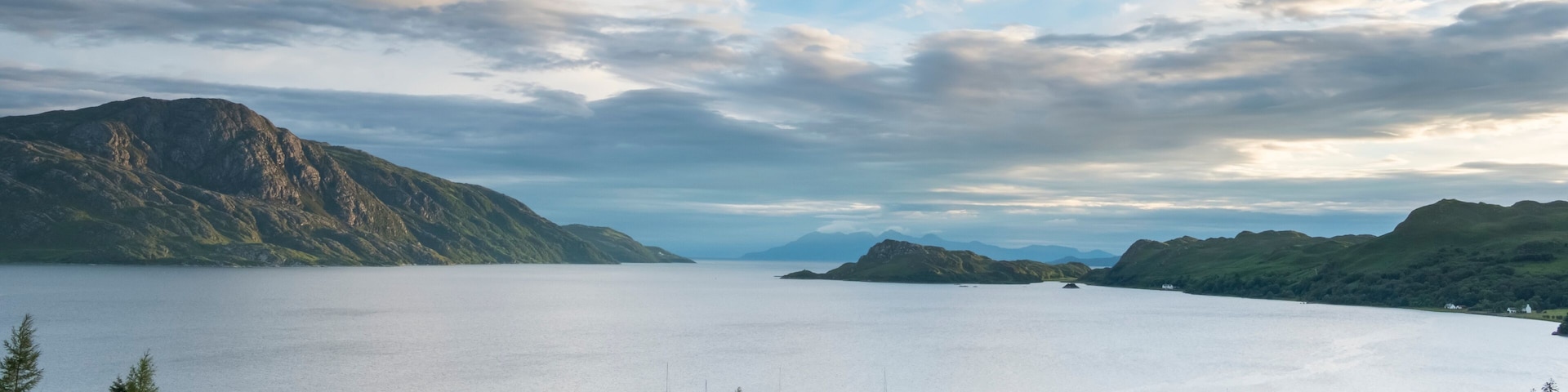 A calm lake surrounded by mountains and a pier with boats.