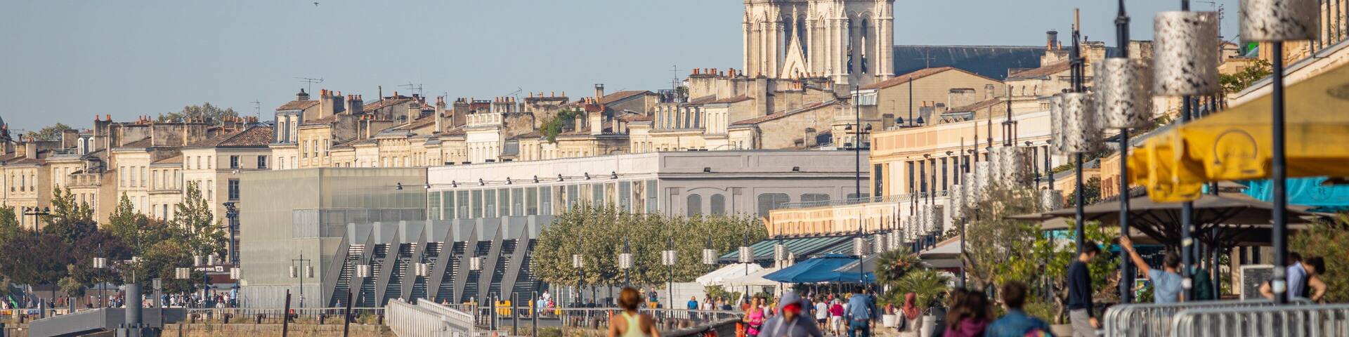 A riverside promenade with a cathedral in the background.