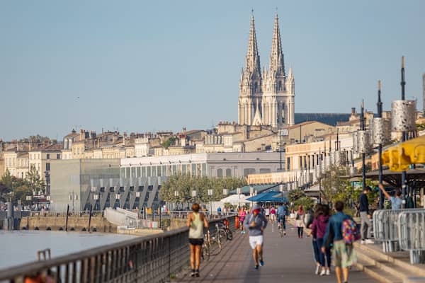 A riverside promenade with a cathedral in the background.
