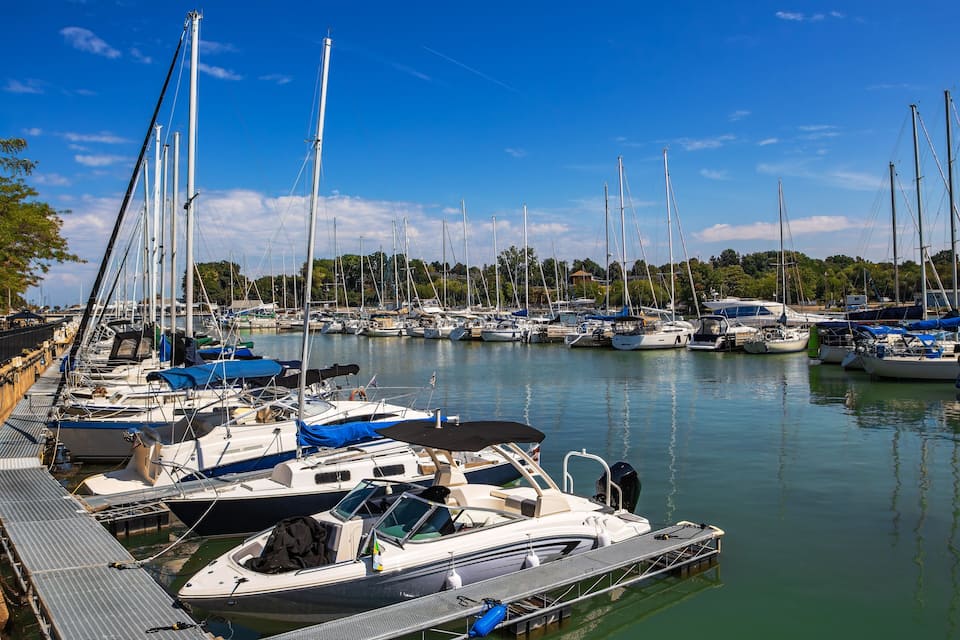 Ein Yachthafen mit verschiedenen Booten an den Stegen, eine Holzpier und ein klarer, blauer Himmel.