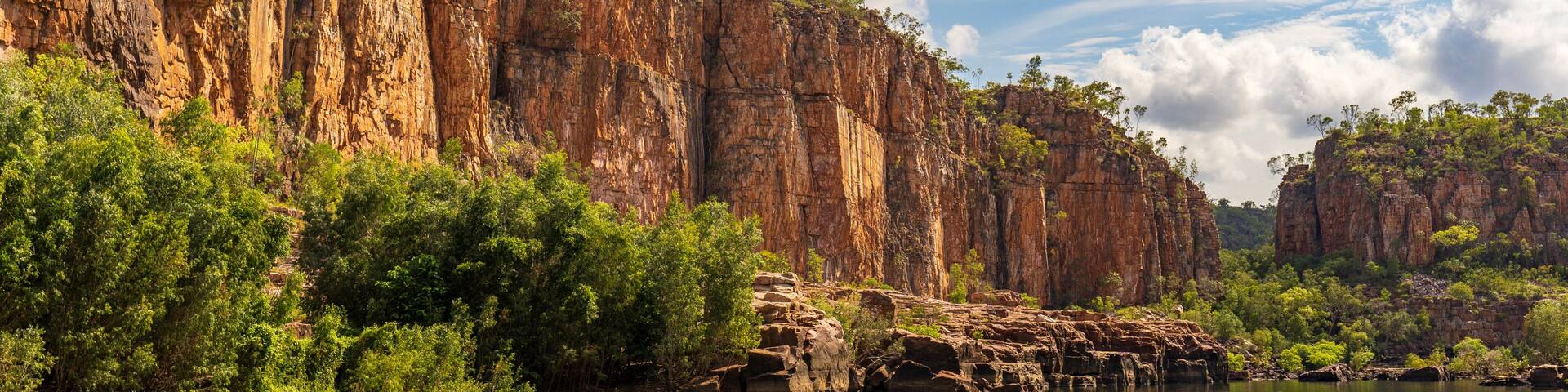 A river with rocky cliffs and dense green foliage.