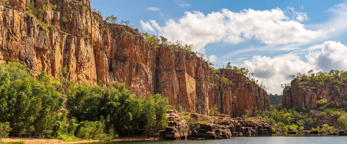 A river with rocky cliffs and dense green foliage.