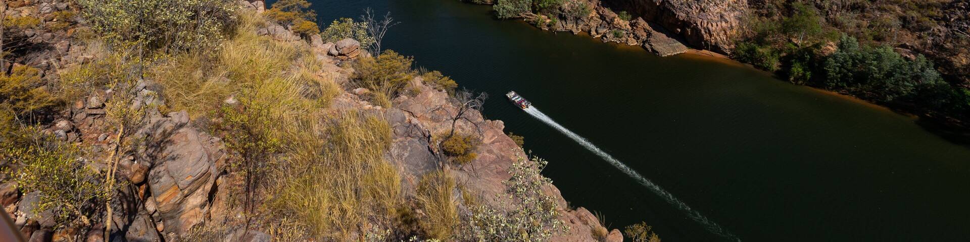 A river winding through a rocky gorge with sparse vegetation and a clear sky.
