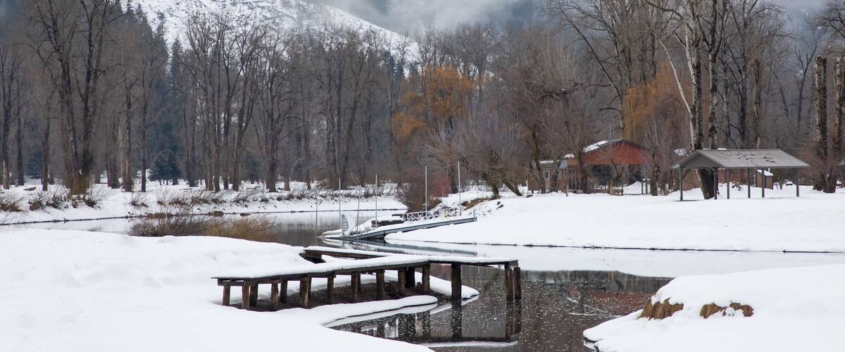 Original winter photograph of a river running through the snow covered riverbanks with a lone dock covered with ice