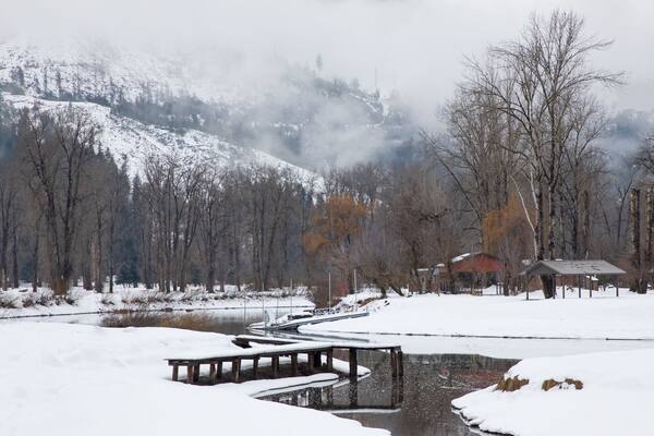Original winter photograph of a river running through the snow covered riverbanks with a lone dock covered with ice