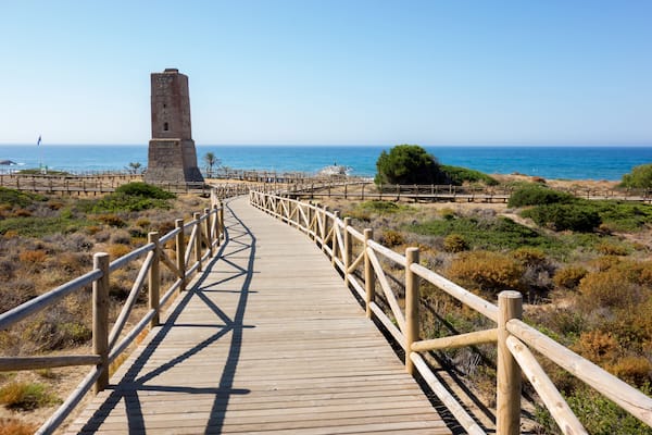 Une promenade en bois mène à une tour de pierre située au bord de la mer.
