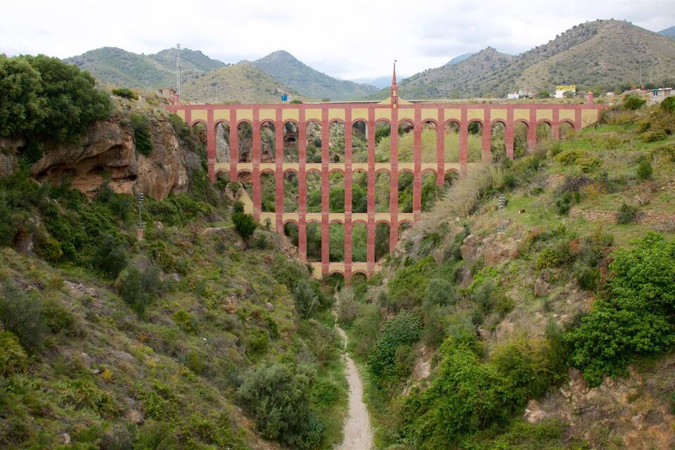 A bridge with arches over a valley with a path leading to it.