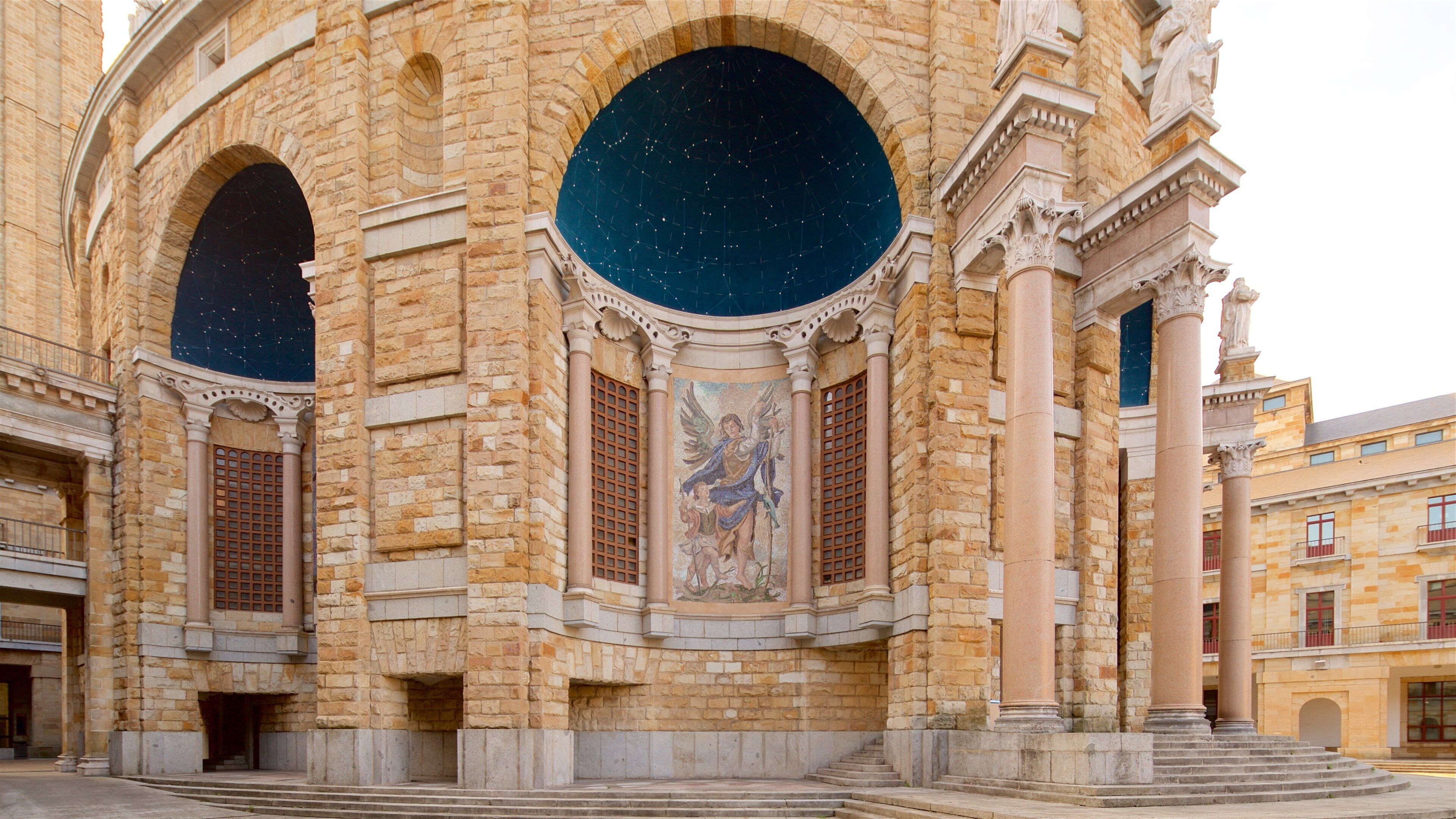 A historic building with large arched windows and a mural of an angel.