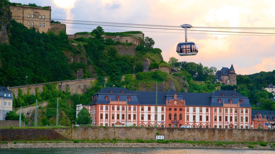 A historic building with red and white architecture, a cable car, and a castle on a hill.