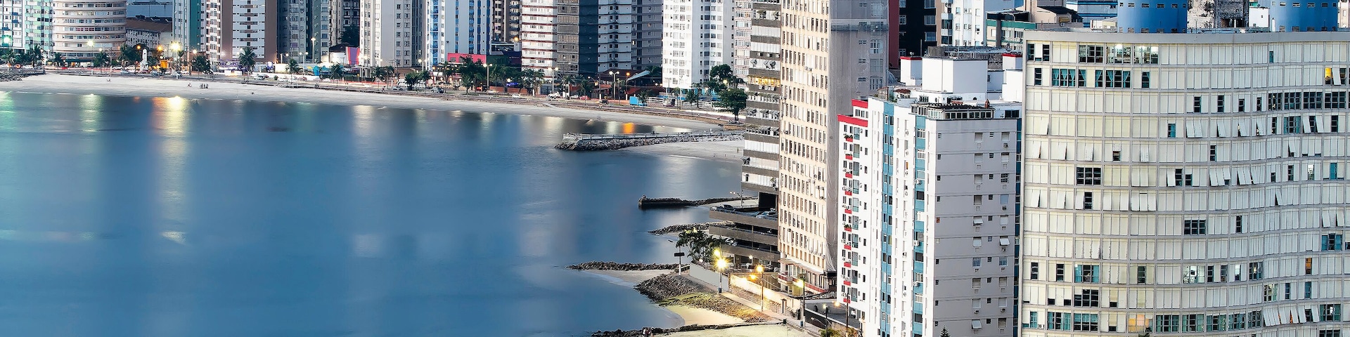 Urbanized coast, tall buildings near to the beach of a coastal city at dusk, when city lights begin to turn on. Paulista coast, Sao Vicente city - SP Brazil.