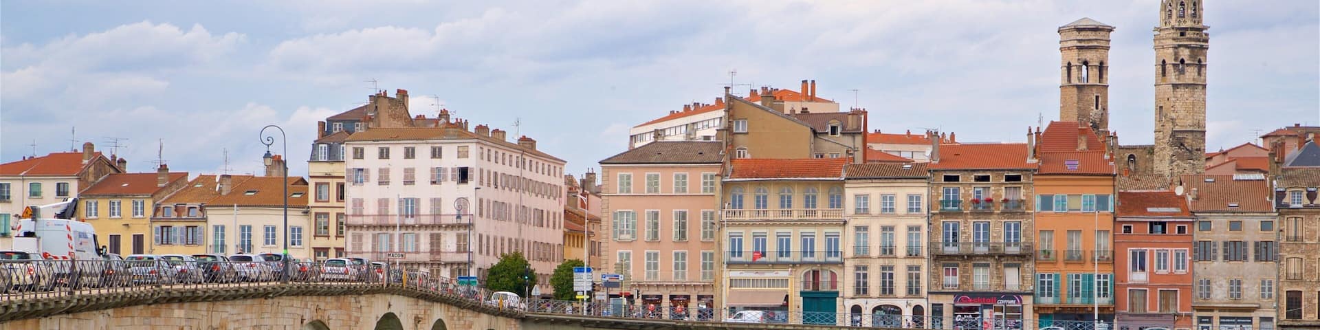 A stone bridge over a river with historic buildings and a tower in the background.
