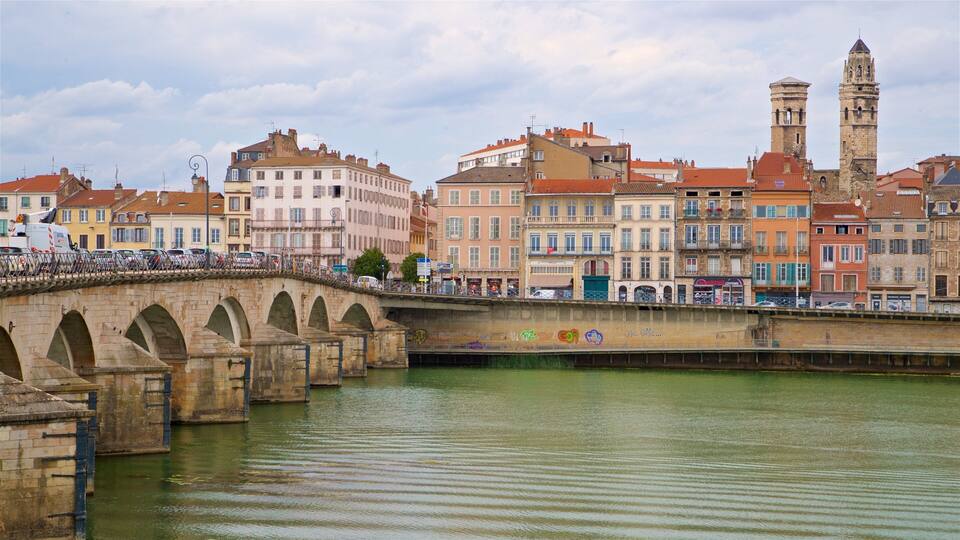 A stone bridge over a river with historic buildings and a tower in the background.