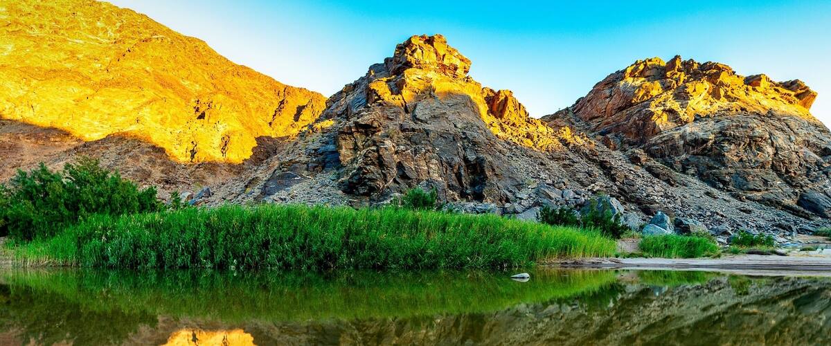 A mountain range with a clear reflection in a calm body of water.