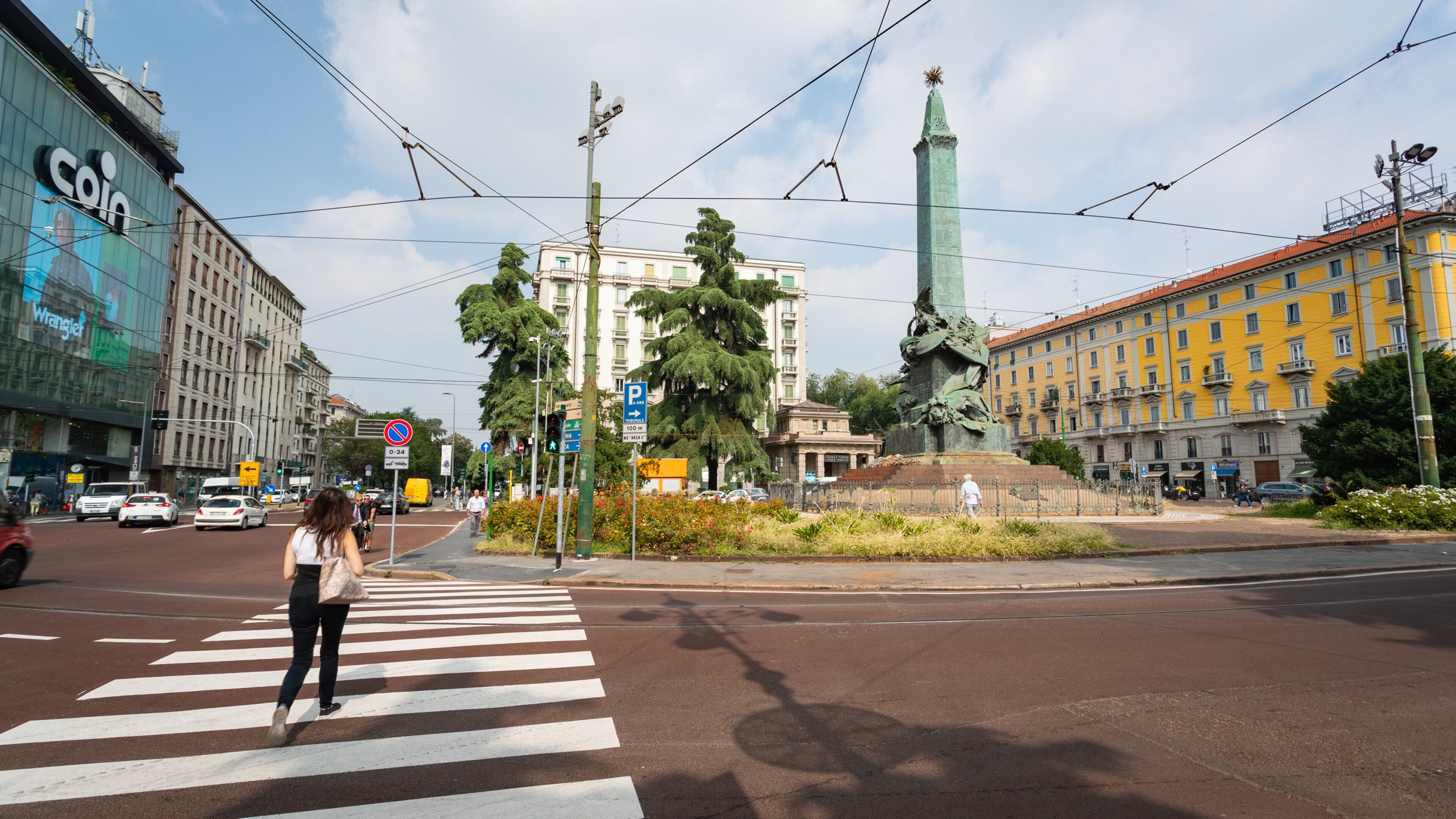 Un passage piéton orné d’une statue au centre, entouré de bâtiments et avec un ciel dégagé.