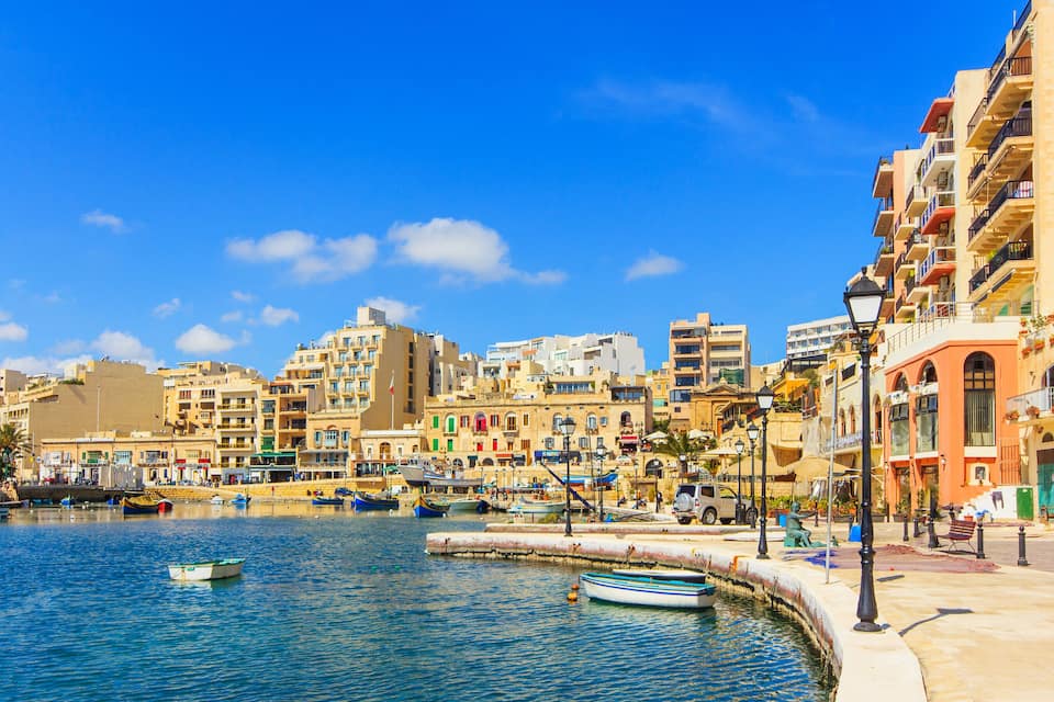 Paesaggio costiero con una marina, barche ed edifici colorati.