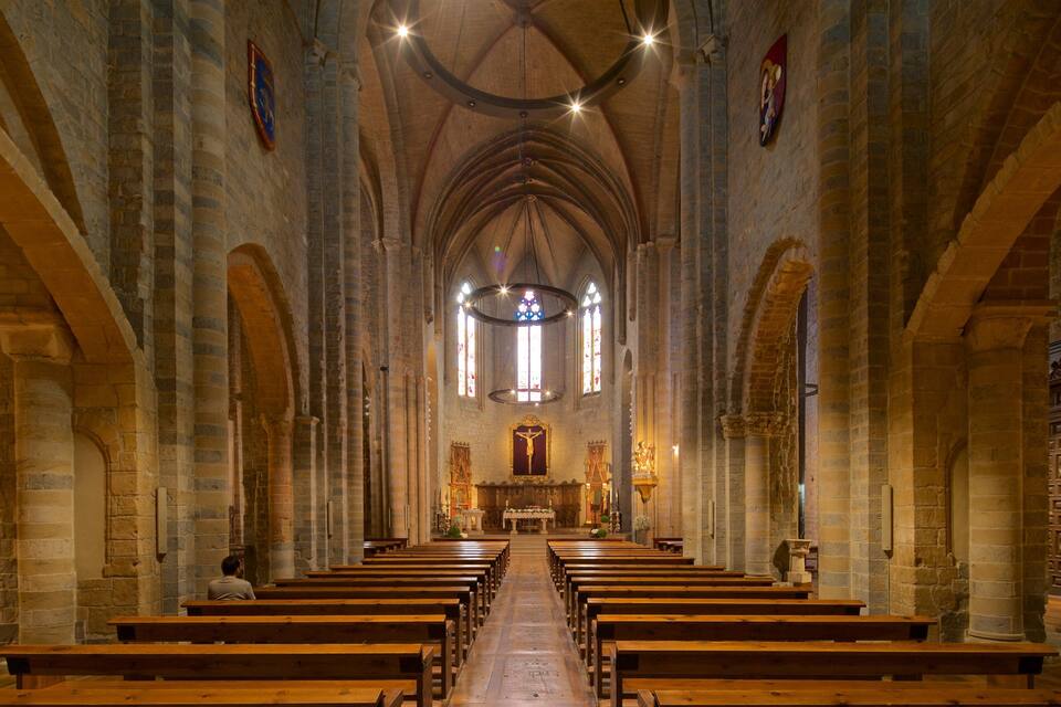 Een kerkinterieur met houten banken, een centraal altaar en gebrandschilderde ramen.