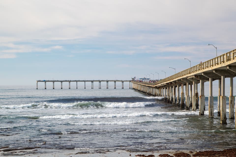 Um cais que se estende para o oceano, com ondas quebrando.