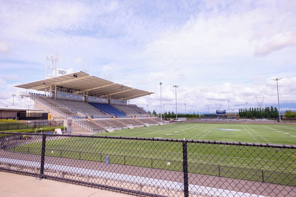 A large, empty sports stadium with a grassy field and bleachers.