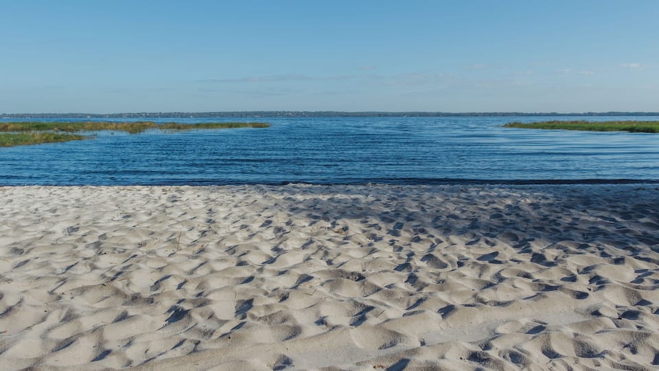 A sandy beach with a calm blue sea and distant shoreline.