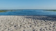 A sandy beach with a calm blue sea and distant shoreline.